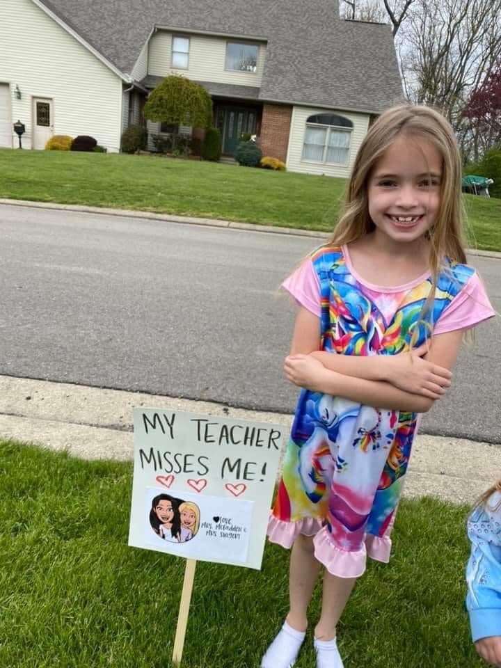 Student posing with sign that says "My teacher misses me!"
